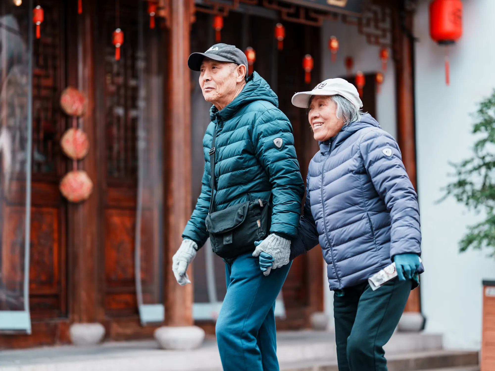 A smiling senior couple walking hand in hand along a quiet heritage street, enjoying an unhurried journey