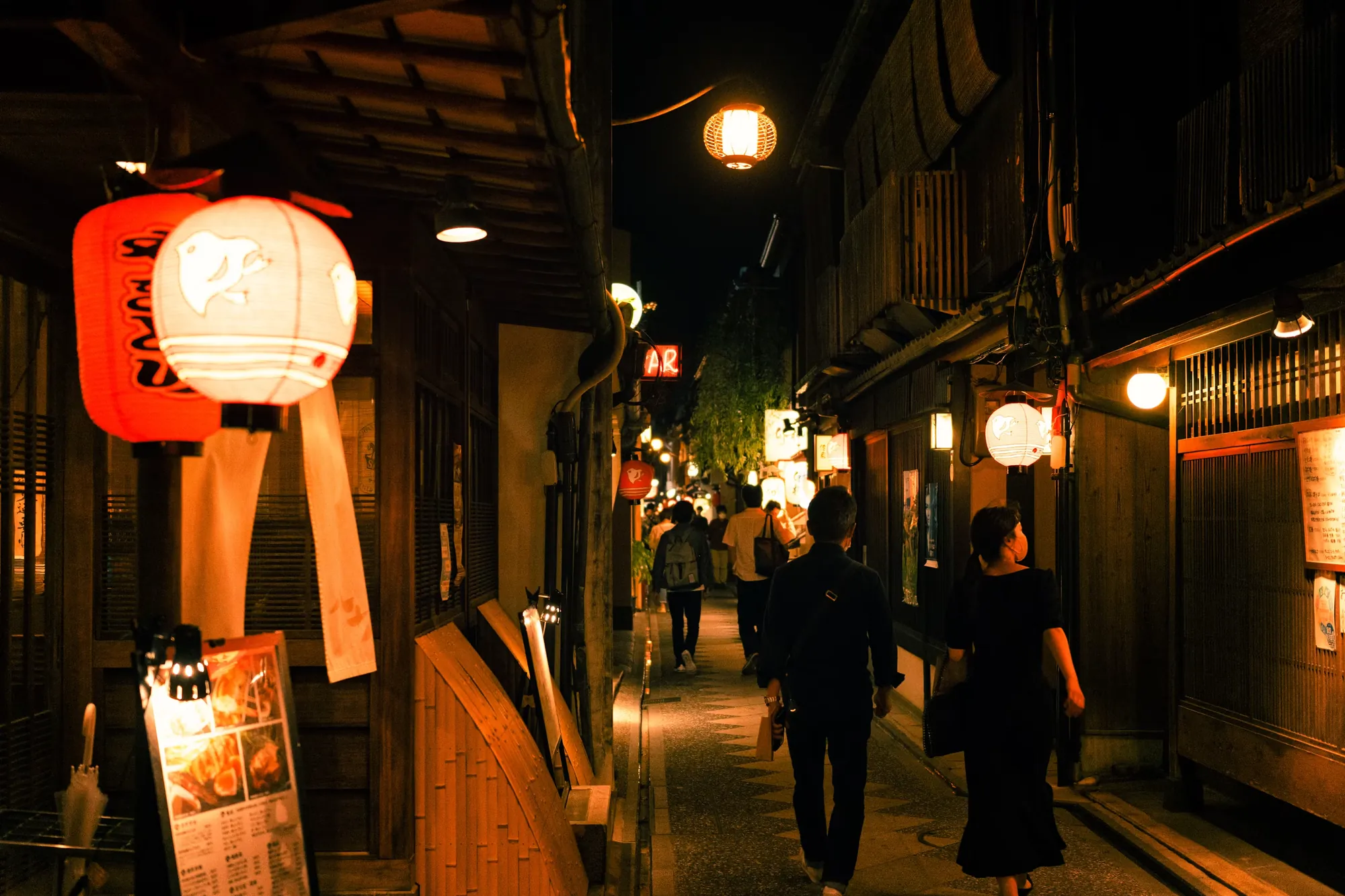 A quiet Kyoto lane glowing with lanterns in the evening